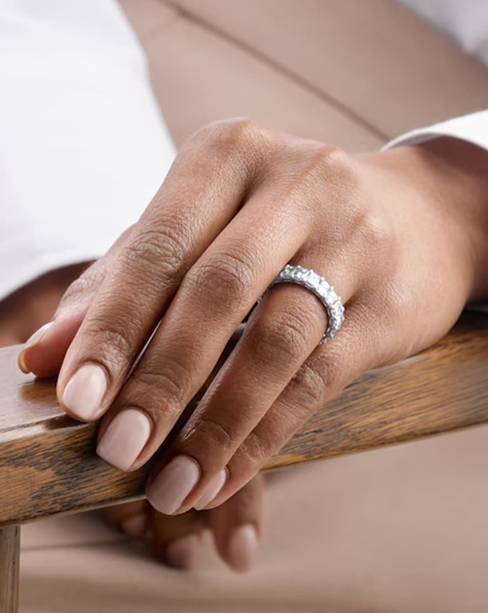 Close up of a woman wearing an Emerald Cut Eternity Ring on her hand.