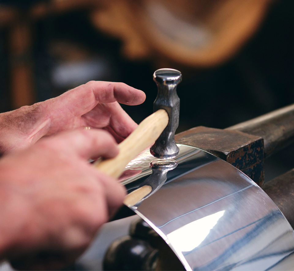 A craftsman shaping silver with a tool