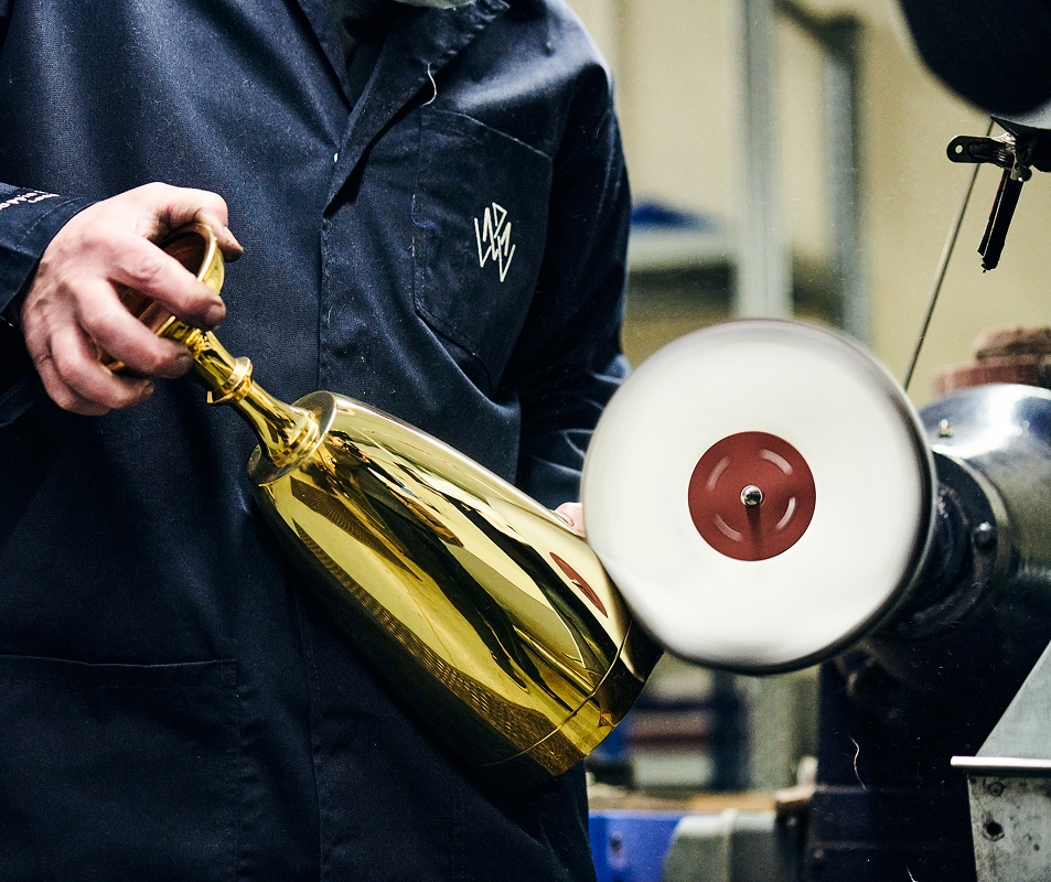 Craftsperson polishing a handcrafted trophy using traditional finishing techniques